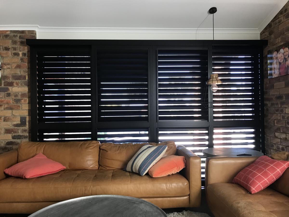 Infinity Shutters in the living room with leather brown sofa and pillows