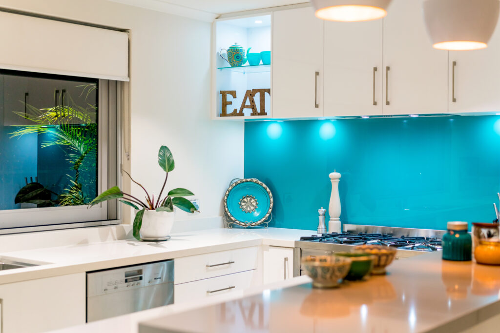 Kitchen interior with colourful decor and blue glass splashback.