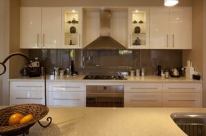 Modern kitchen, with granite benchtops and reflective glass splashback.