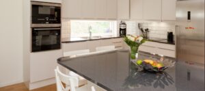 A kitchen with a black countertop and glass splashbacks